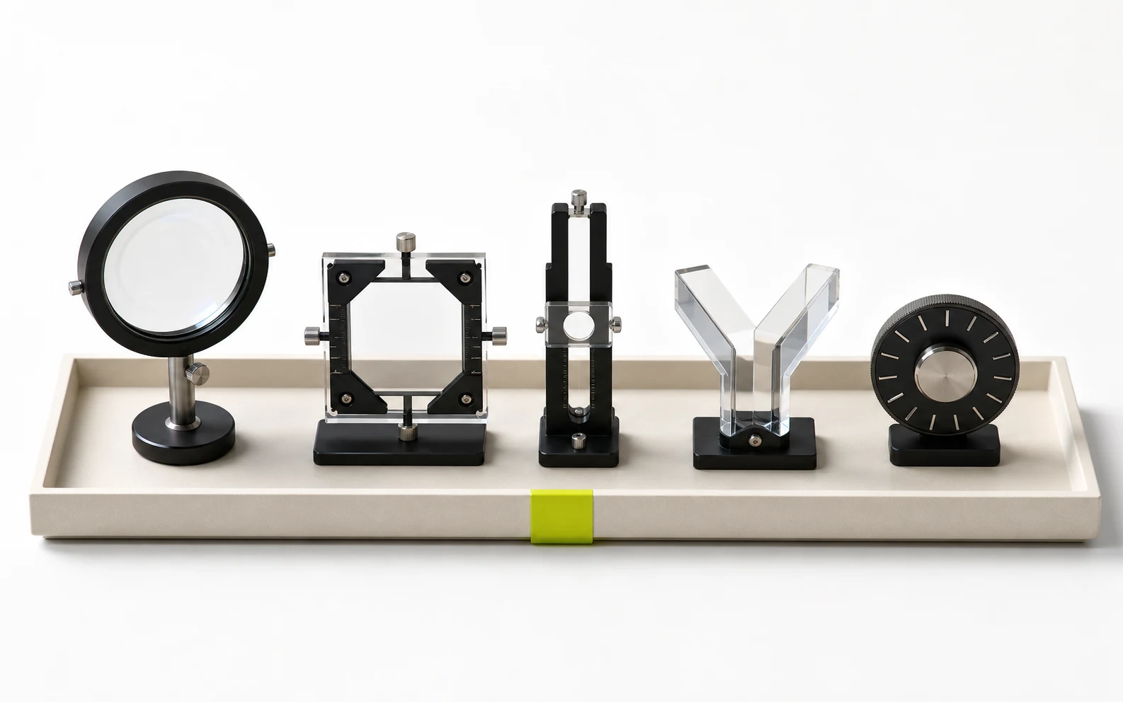 Five distinct optical editing instruments sit in a white museum tray, with a lime selection tab clipped beneath the collection.